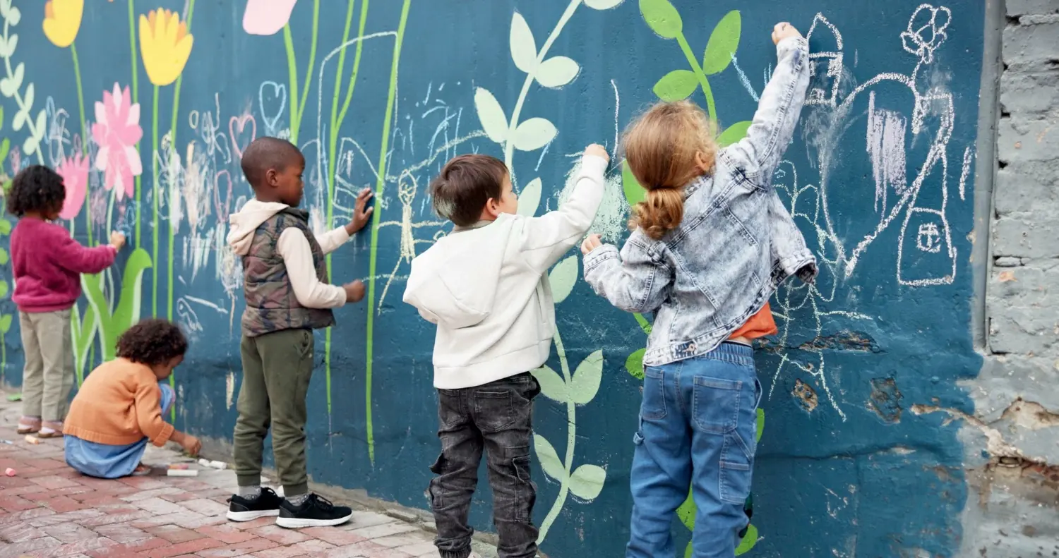 Children drawing with chalk on a painted mural wall